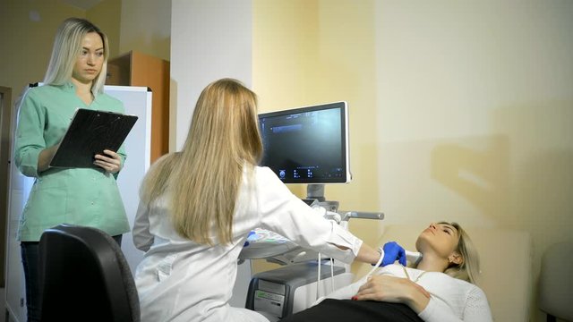Doctor Taking A Sonogram Thyroid gland, nurse writes and helps the doctor.
