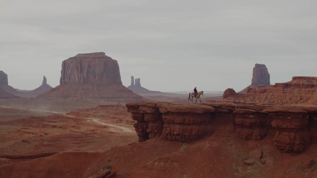 Model released Navajo man on horseback in front of red rock formations in Monument Valley, Arizona, USA. 4K UHD 60 FPS SLOW MOTION