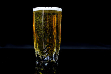 glass with beer, black background, yellow beer.