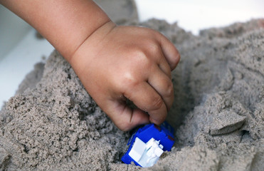 Child playing with a toy in the kinetic sand