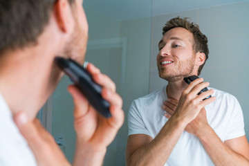 Young man shaving neck and jawline in the morning using electric shaver / clipper. Morning routine...