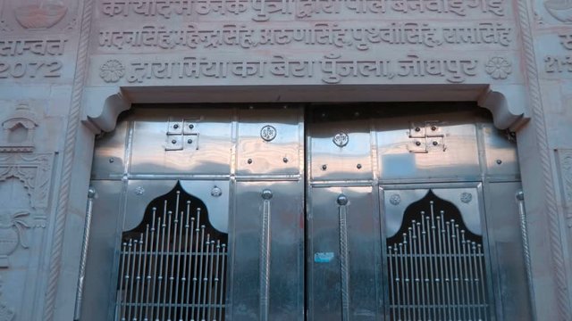 The entrance to the temple with beautiful metal shiny chrome door with swastika and around the traditional pattern on the wall, in the city of Pushkar, India, one of the sacred pilgrimage sites in Hin