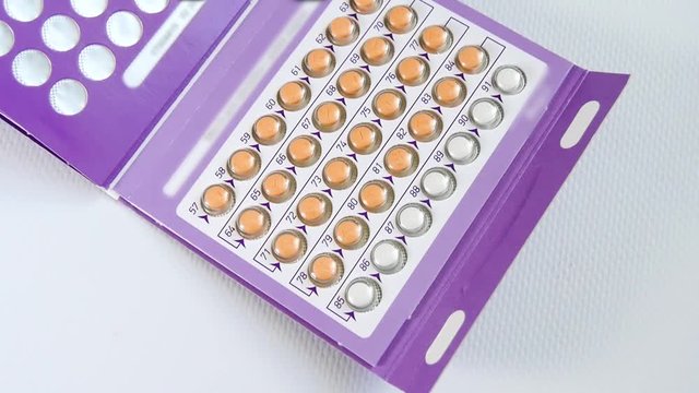 The camera tracks the packing of combined oral contracts lying on the table. Conception of pregnancy planning, oral pills, contraceptive methods.