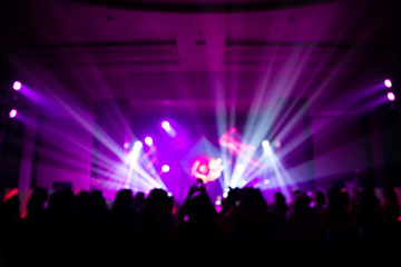 Fototapeta na wymiar Defocused entertainment concert lighting on stage with people silhouette