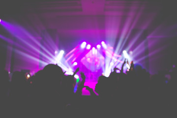Defocused entertainment concert lighting on stage with people silhouette