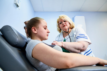 Obraz premium Experienced doctor fat woman taking care of a sick girl on the couch in the medical office