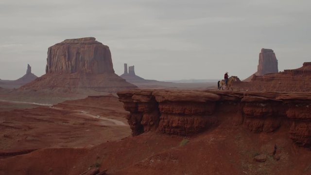 Model released Navajo man on horseback in front of red rock formations in Monument Valley, Arizona, USA. 4K UHD 60 FPS SLOW MOTION