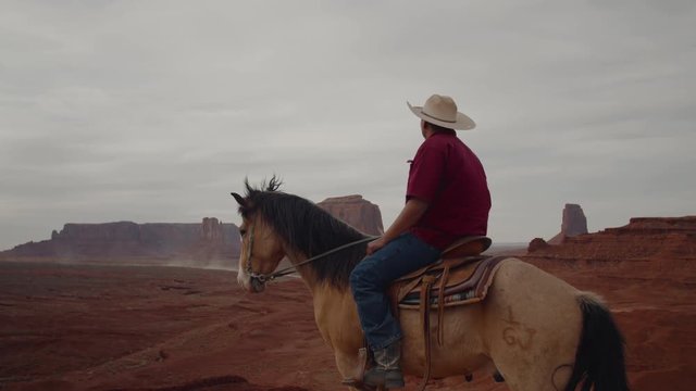 Model released Navajo man on horseback in front of red rock formations in Monument Valley, Arizona, USA. 4K UHD 60 FPS SLOW MOTION