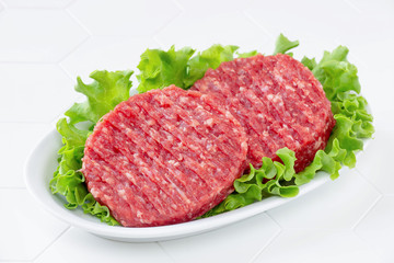 Raw mince meat beef burgers on a white plate