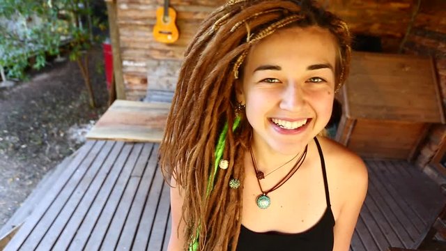 closeup portrait of a young pretty smiling woman with dreadlocks, cheerfully looking at the camera