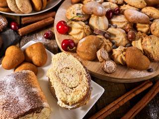 Oatmeal cookies and sand chocolate cake with cherry berry and crispy wafer rolls with cream on cutting board on wooden table in rustic style. Limitations for diabetics. It has pleasant taste.