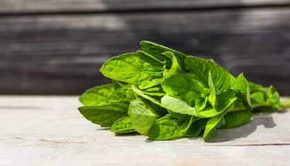 Fototapeta premium a bouquet of fresh mint on a wooden surface in sunlight with a copy of space