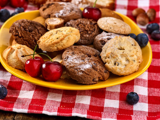 Fototapeta na wymiar Oatmeal Cookies and sand chocolate cake with blueberries on wooden table in farm style close up. Table setting breakfast for two. Delightful, unique taste.