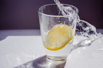 glass of water with lemon and ice on white background