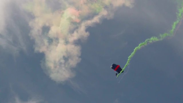 Paracadutisti si lanciano con fumogeni colorati al seguito. Esibizione aerea spettacolare.