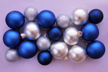 Christmas balls in blue and white colors on lilac background