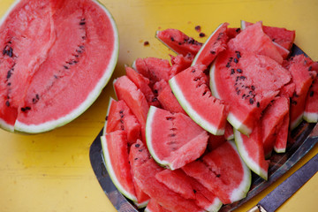 Juicy fresh watermelon sliced into wedges on yellow color table