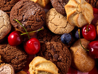 Cookies and sand biscuit on tier cake stand with blueberry chocolate on kitchen on picnic table in rustic natural style. Dessert in cafe. Close-up.