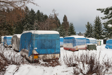 Campers covered by snow in winter season, campers covered with plastic and protective tarp.