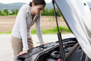 Woman having a car breakdown and staring at the engine