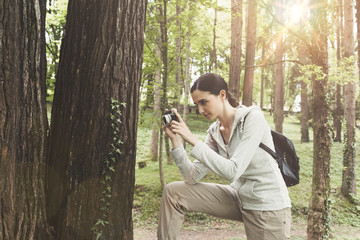 Fototapeta na wymiar Young woman walking in nature and taking pictures