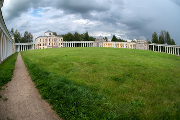 Fototapeta na wymiar Architectural ensemble Manor Znamenskoye-Rayok. The manor house and the circular colonnade connecting it with the side wings (carriage and greenhouse) and the main gate opposite to it.