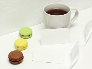 Mockup business cards on white background with macaron, ribbon and cup of coffee