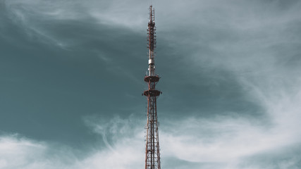 Radio tower antenna on a background of blue sky with white clouds. Telecommunication transmitter...