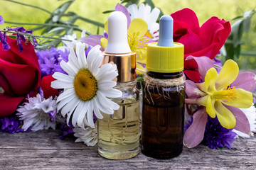 Natural essential oil with wild flowers on wooden background.