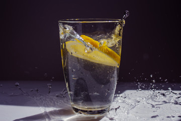 glass of water with lemon on black background
