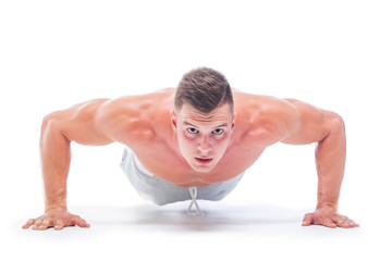 Fototapeta na wymiar Sports man doing push ups isolated on a white background. Strong Athletic Man - Fitness Model showing his perfect body.