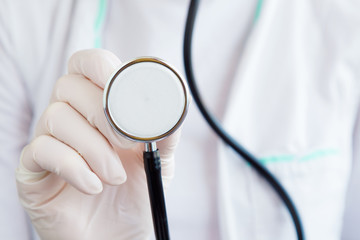Doctor hand in rubber protective glove holding stethoscope. Tool for heartbeat and noise of lungs...