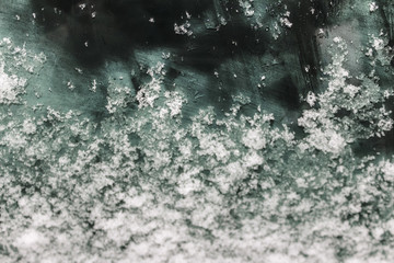 dark blue glass in hoarfrost and snow, car tinted glass in the texture of frost and snow, the situation outside the window, winter frozen glass background, melting ice and snow on the glass