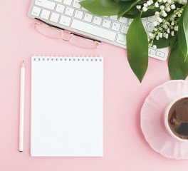 Pink flat lay top view women's office desk . Female workspace with laptop, white spring flowers...