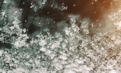 dark blue glass in hoarfrost and snow illuminated from the side by the sunset, car tinted glass in the texture of frost and snow, the situation outside the window, a winter frozen glass background