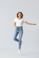 Jumping young woman in jeans on white background