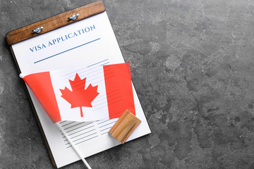 Visa application form, stamp and Canadian flag on table. Concept of immigration