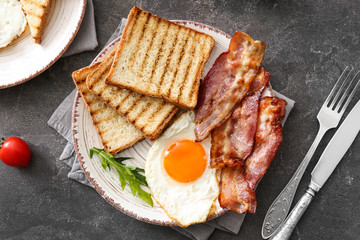 Plate with tasty grilled bread, fried egg and bacon on table