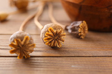 Dried poppy heads with seeds on wooden table