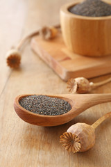 Spoon with poppy seeds on wooden table