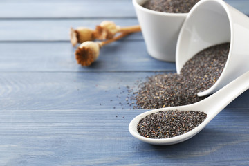 Spoon and bowl with poppy seeds on wooden table