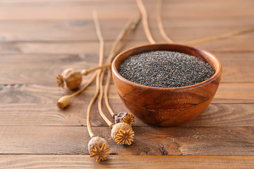 Bowl with poppy seeds on wooden table