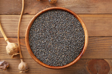 Bowl with poppy seeds on wooden table