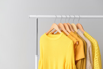 Rack with clothes after dry-cleaning on light background