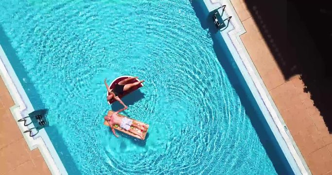 Couple of active senior people enjoy the vacation or retired lifestyle on a blue swimming pool with funny lilos - happiness and relax for couple of mature caucasian - summer holiday vacation concept
