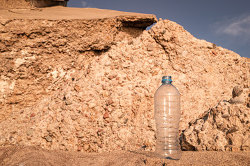 water flows out of a plastic bottle on the sea sand. water saving. last water drop