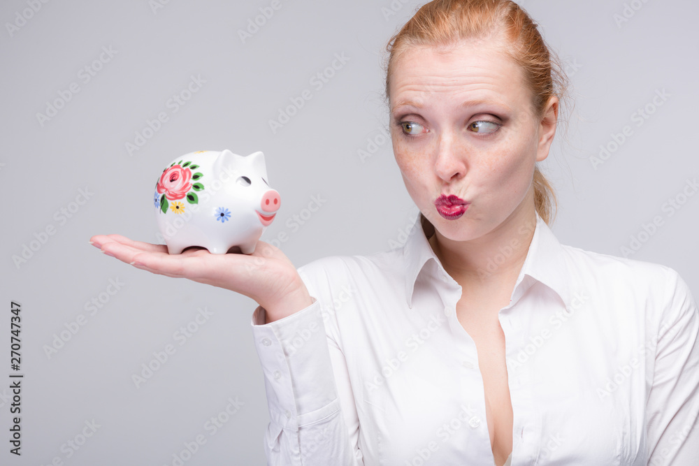 Wall mural young red haired woman wants to kiss her piggy bank