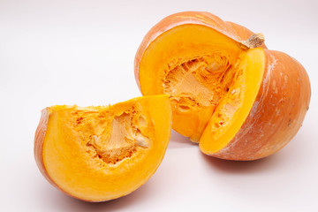 Quarter cut from the whole ripe pumpkin, side view, on a light background