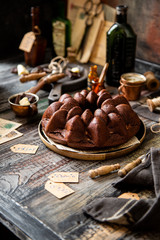 Delicious homemade chocolate bundt cake on wooden plate stands on rustic table