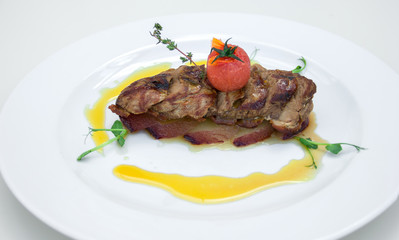 tender juicy meat it meat slices on a plate with sauce and tomato, restaurant table setting, white background